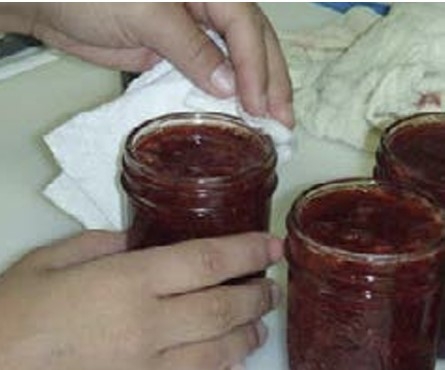 wiping the edge of a jar with a paper towel