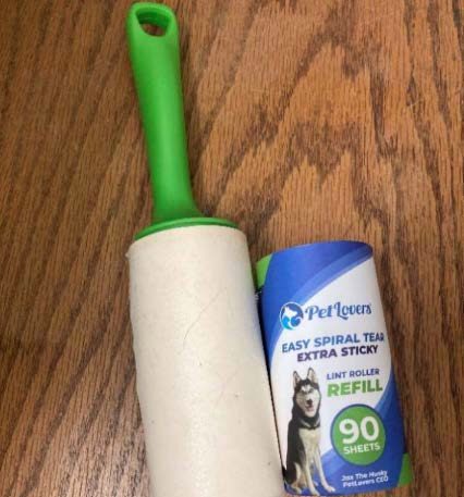 Figure 4.  An extra sticky lint roller with a green handle beside an unopened refill roll. 