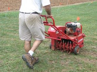 A core aerator (plugger)  is being used to prepare an existing site for introduction of new grass seed.