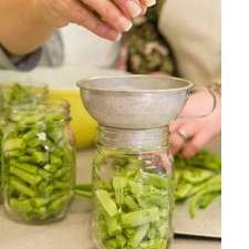 Photo of someone filling jars with green beans.