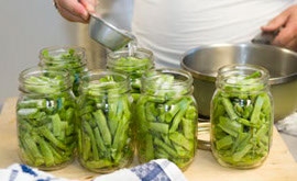 Photo showing adding water to the jars filled with green beans.