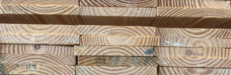 Close up of the ends of 3 stacks of boards. Wide growth rings are visible on the ends.  