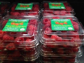 Photo showing raspberries in clear plastic containers, stacked in three layers.