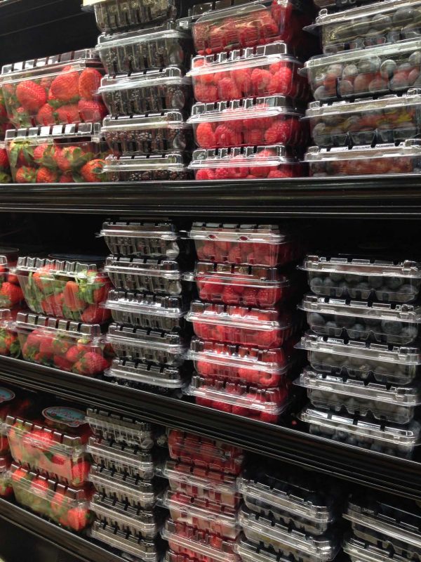 Rasberries, blueberries, blackberries nd strawberries on display in a supermarket refrigerator