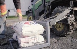 A large sack for farming on a lift connected to a utility vehicle 