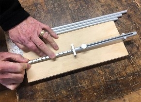 A pair of hands using a click ruler to measure a board of wood.