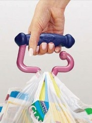 Hand holding EZ Carry handle with plastic bags attached. The handle is made up of a flat dowel that the hand holds and a hook that holds plastic bags (or other items)
