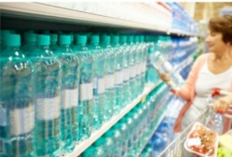 A woman looking to purchase bottled water in the grocery store to prepare for an emergency.