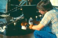 Image of boy with nozzle output determination with calibrated containers and stopwatch.