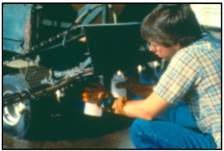 Image of boy with nozzle output determination with calibrated containers and stopwatch.