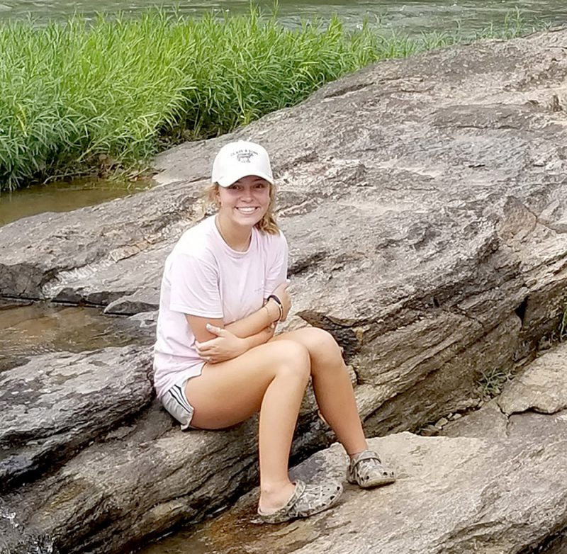 photo of a girl sitting on a stone by the river