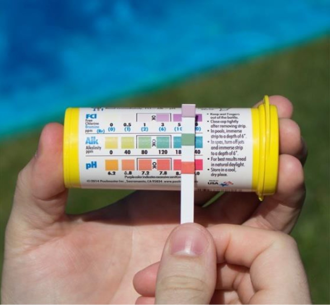 A picture of a hand holding a simple test kit with a test strip.