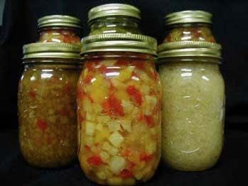 Two rows of three clear glass jars with lids, each containing a home canned food. 