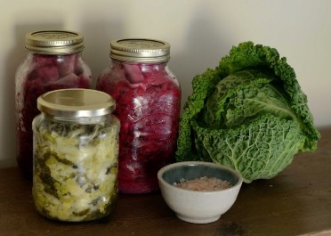 a photo of Sauerkraut in jars with a cabbage and salt.