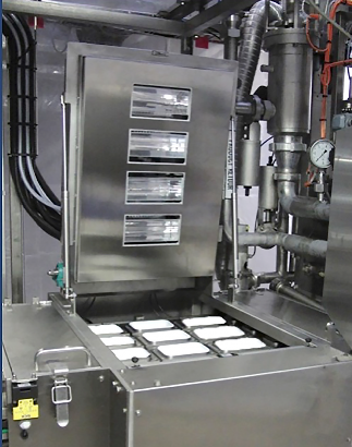 A large stainless steel machine with its lid raised and nine white rectangular food containers visible inside. 