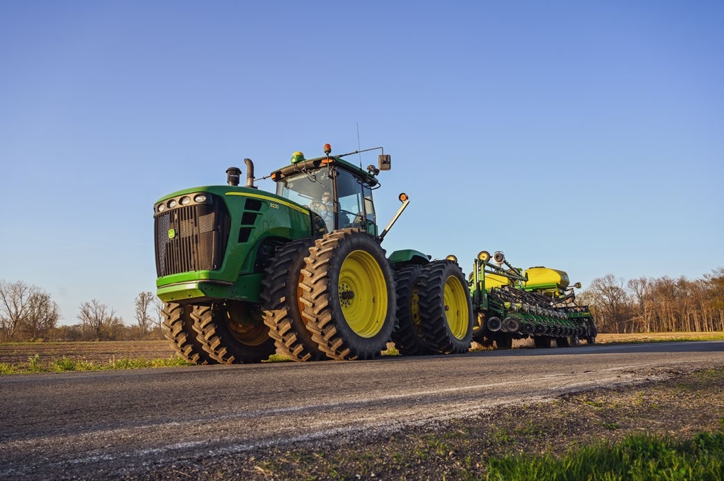 A picture containing a tractor working in an agricultural field. 