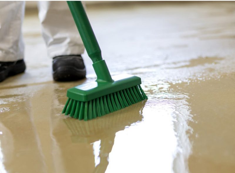 Picture of man brushing floor, wet floor.