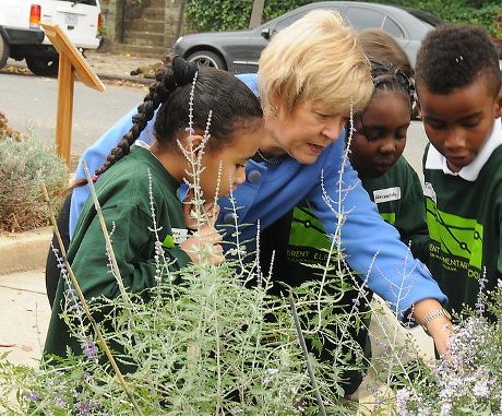 A volunteer showing a group of children some plants.