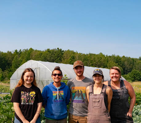 A group of volunteers standing in front of a greenhouse.