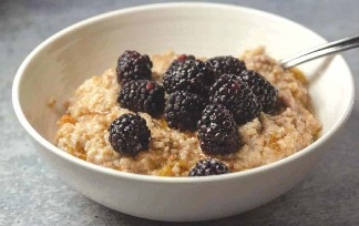 Bowl of oatmeal with fresh blackberries on top.