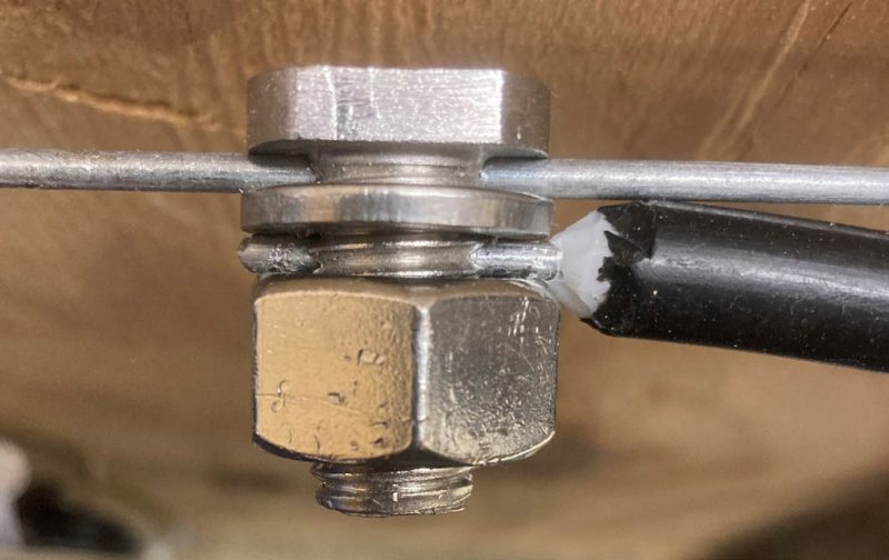 An insulated cable extends outward to the right from a split-bolt connector.